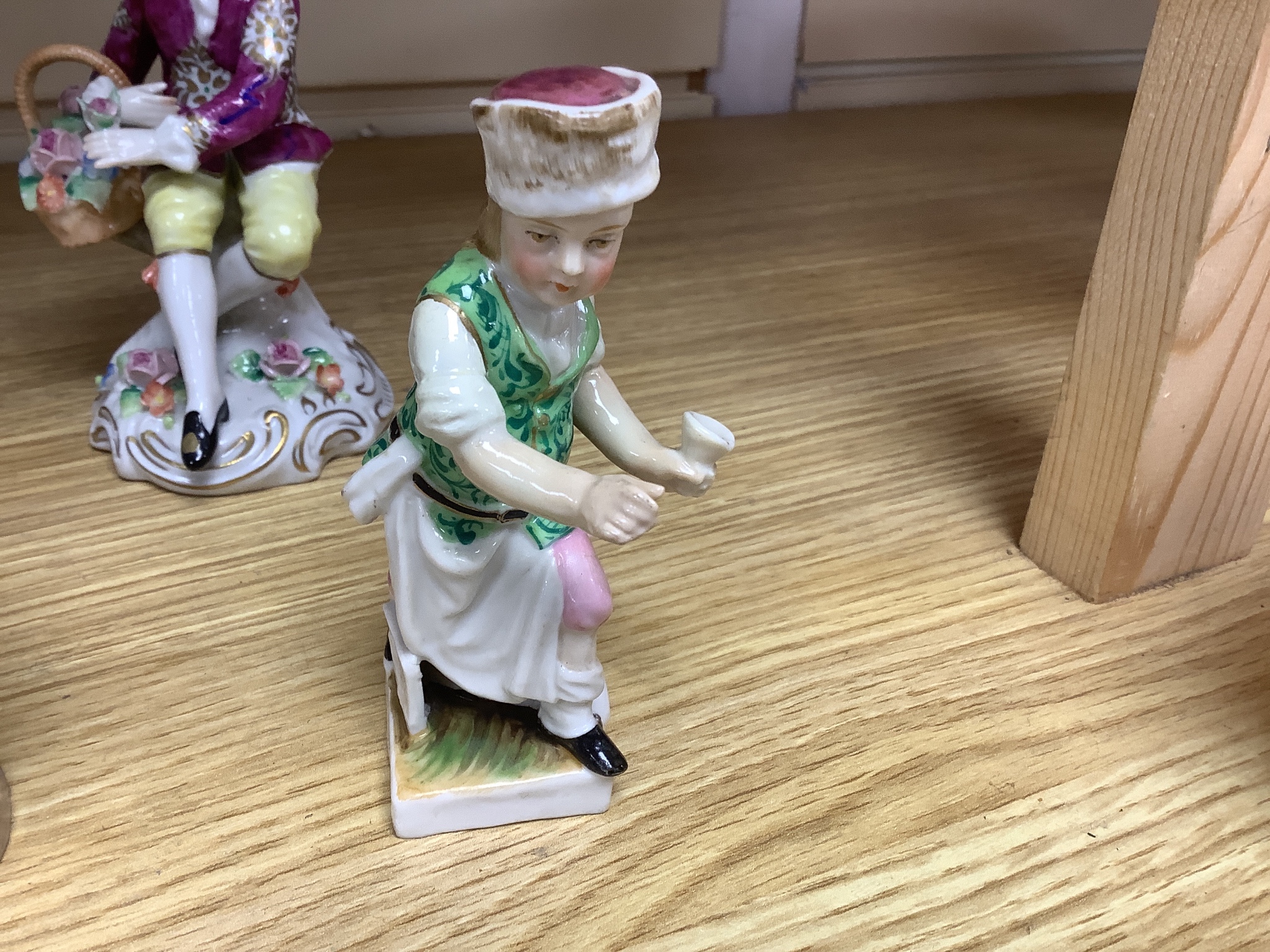 A late 19th century Meissen figure of a boy holding a garland of flowers, and a Sampson Hancock Derby figure and three other continental porcelain figures, tallest 18 cms high.